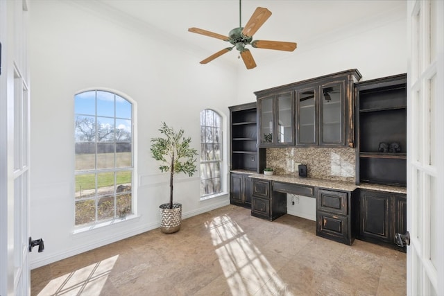 office area with built in desk, ceiling fan, plenty of natural light, and ornamental molding