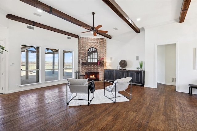 living room featuring ceiling fan, dark hardwood / wood-style floors, beamed ceiling, and a fireplace