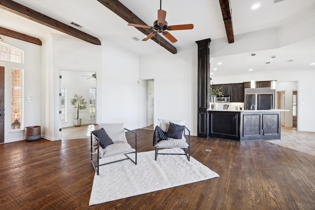 living room featuring a wealth of natural light, ceiling fan, beamed ceiling, and dark hardwood / wood-style flooring