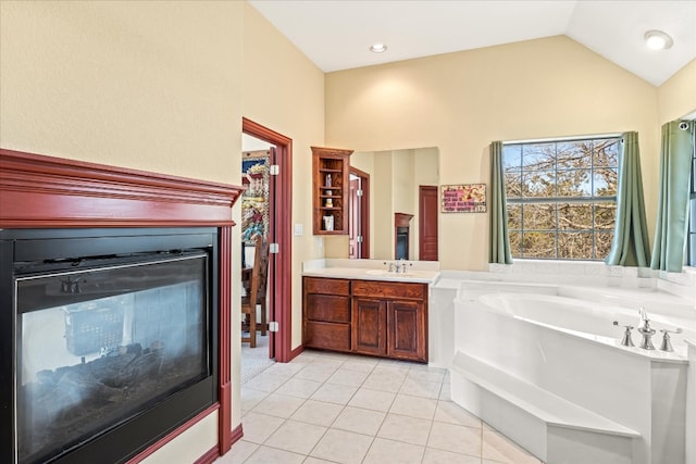 bathroom with tile floors, large vanity, vaulted ceiling, and a tub