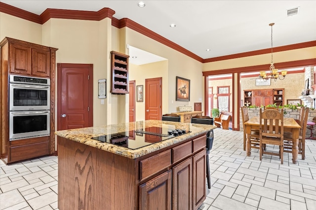 kitchen with pendant lighting, a kitchen island, a chandelier, double oven, and black electric stovetop