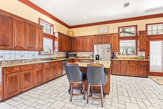 kitchen with light stone countertops, a kitchen island, a wealth of natural light, and stainless steel appliances