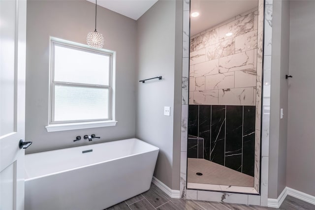 full bath featuring wood finish floors, a soaking tub, baseboards, and walk in shower