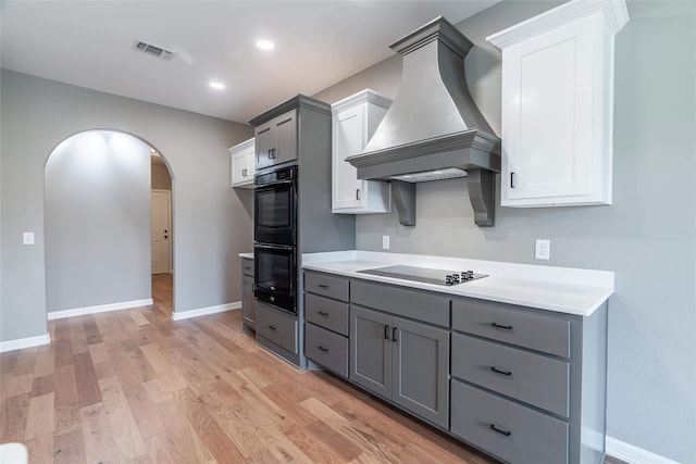 kitchen with visible vents, arched walkways, custom exhaust hood, gray cabinetry, and black appliances