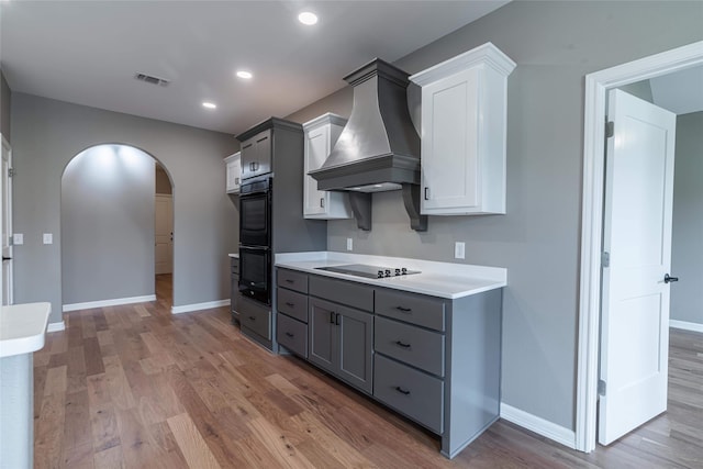 kitchen with visible vents, arched walkways, custom exhaust hood, gray cabinets, and light countertops