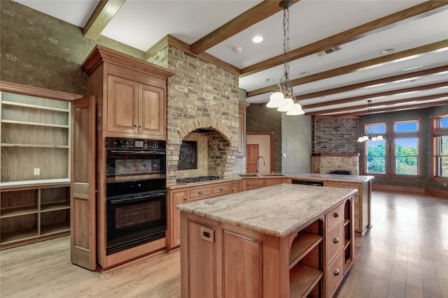 kitchen with light hardwood / wood-style floors, a center island, a fireplace, black double oven, and hanging light fixtures