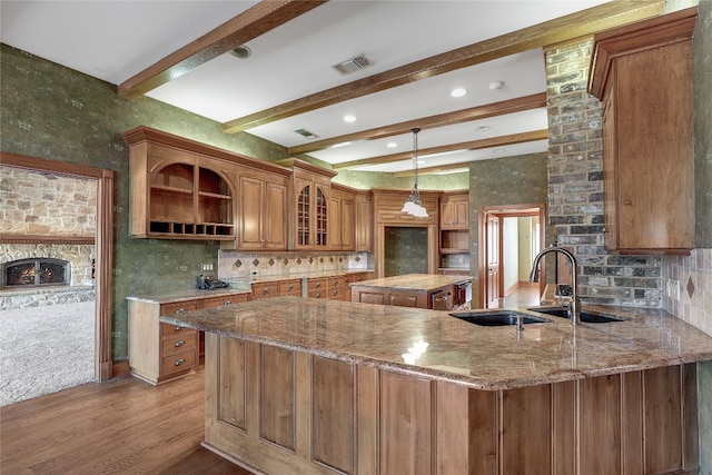 kitchen with wood-type flooring, backsplash, light stone counters, and pendant lighting