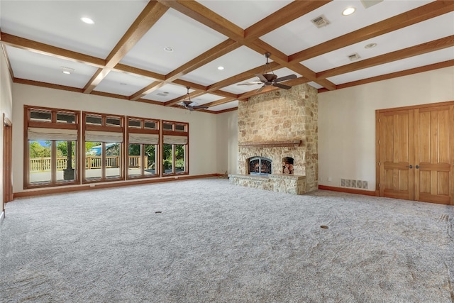 unfurnished living room with coffered ceiling, a stone fireplace, beamed ceiling, and a healthy amount of sunlight