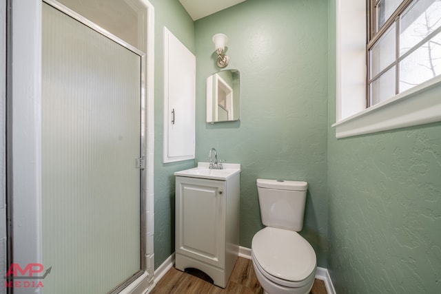 bathroom with hardwood / wood-style flooring, vanity, toilet, and a shower with door