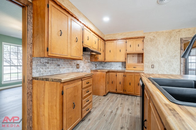 kitchen featuring sink, butcher block counters, black dishwasher, tasteful backsplash, and light hardwood / wood-style floors