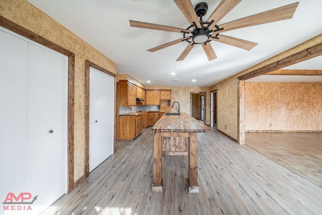 kitchen featuring sink, a breakfast bar, ceiling fan, and light wood-type flooring