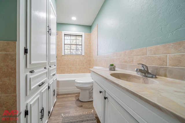 bathroom featuring tile walls, a bathtub, vanity, wood-type flooring, and toilet