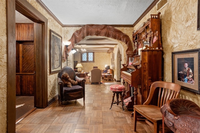 sitting room featuring an inviting chandelier, a textured ceiling, ornamental molding, beam ceiling, and light parquet flooring