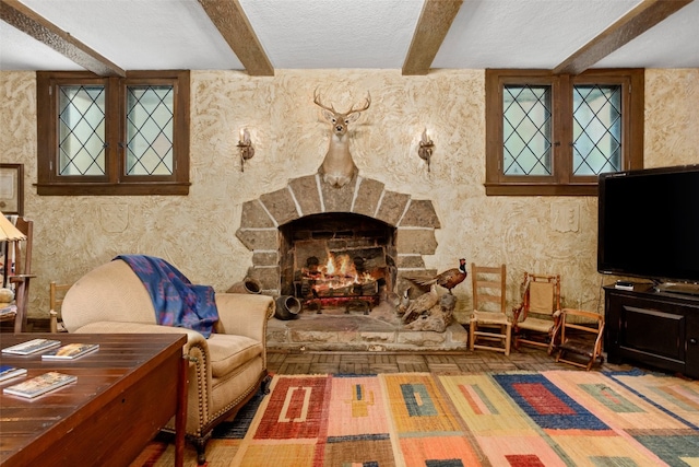 living room featuring a fireplace, beamed ceiling, and a textured ceiling