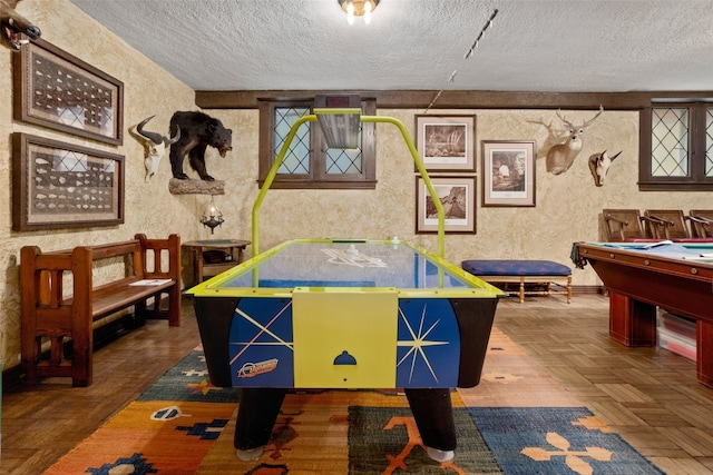 playroom with dark parquet flooring, a textured ceiling, and pool table