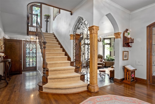 staircase with dark wood-type flooring, ornate columns, and a wealth of natural light