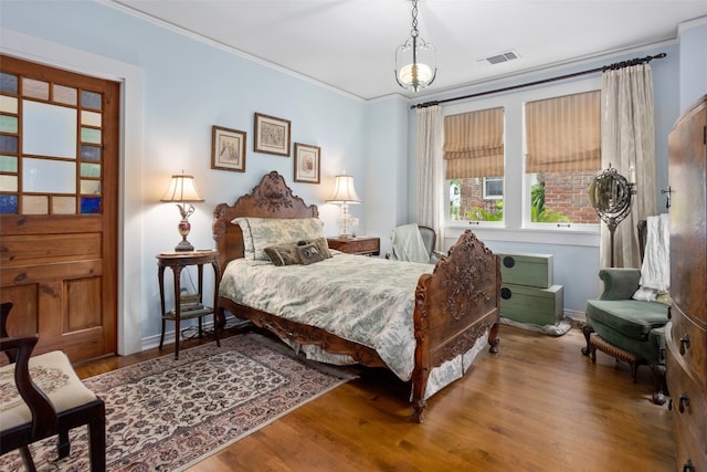 bedroom featuring dark hardwood / wood-style flooring, ornamental molding, and a chandelier