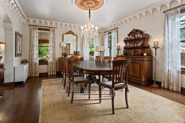 dining area featuring crown molding, dark hardwood / wood-style floors, and an inviting chandelier