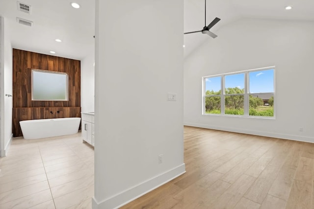 corridor with wood walls, high vaulted ceiling, and light tile flooring