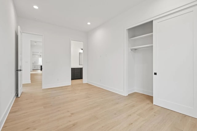 unfurnished bedroom with ensuite bath, light hardwood / wood-style floors, and a closet