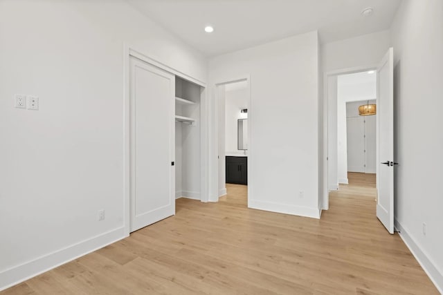 unfurnished bedroom featuring ensuite bath, light hardwood / wood-style floors, and a closet