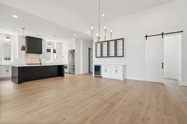 interior space featuring a barn door, light hardwood / wood-style floors, and an inviting chandelier