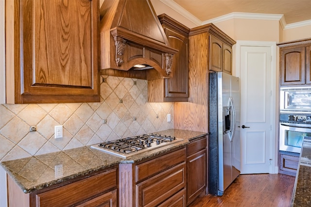 kitchen featuring dark stone counters, stainless steel appliances, custom range hood, and dark hardwood / wood-style flooring