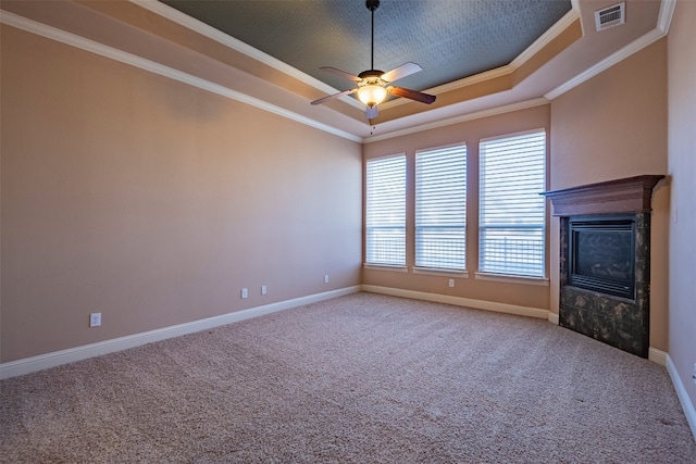 unfurnished living room with ceiling fan, a tile fireplace, a raised ceiling, crown molding, and light carpet