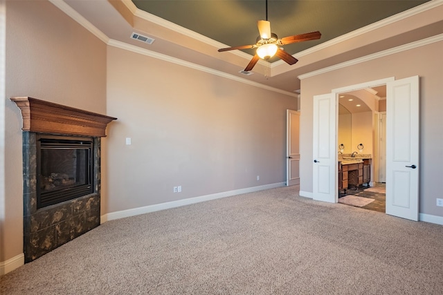 unfurnished bedroom with ceiling fan, a tile fireplace, light colored carpet, and ensuite bathroom