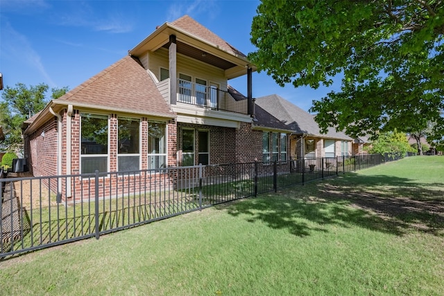 rear view of property featuring a balcony and a lawn