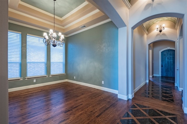 empty room with a notable chandelier, dark hardwood / wood-style floors, a raised ceiling, and ornamental molding