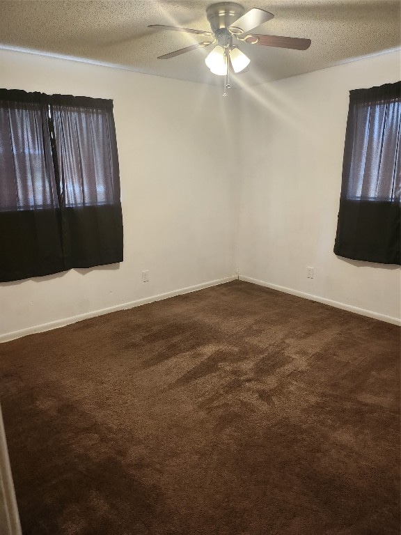 spare room with ceiling fan, a textured ceiling, and dark carpet