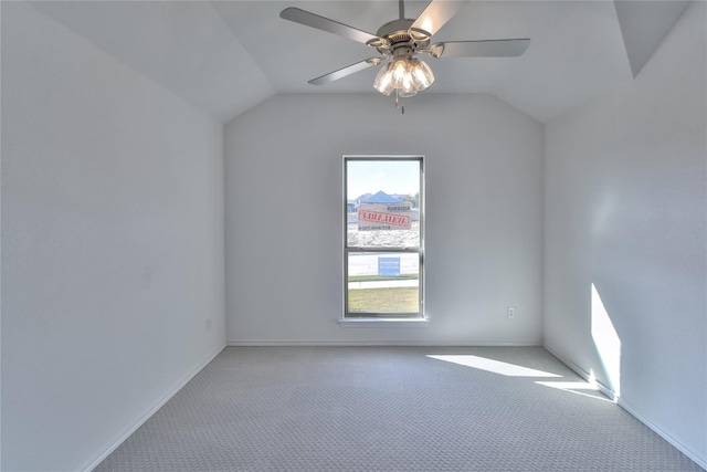 carpeted spare room with ceiling fan and vaulted ceiling