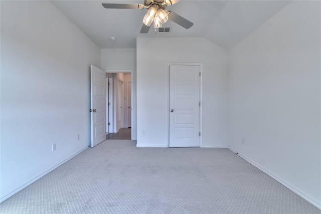 unfurnished bedroom with light colored carpet, vaulted ceiling, a closet, and ceiling fan