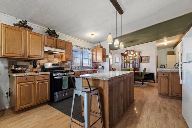 kitchen featuring pendant lighting, a kitchen breakfast bar, light hardwood / wood-style flooring, stainless steel gas range, and an inviting chandelier