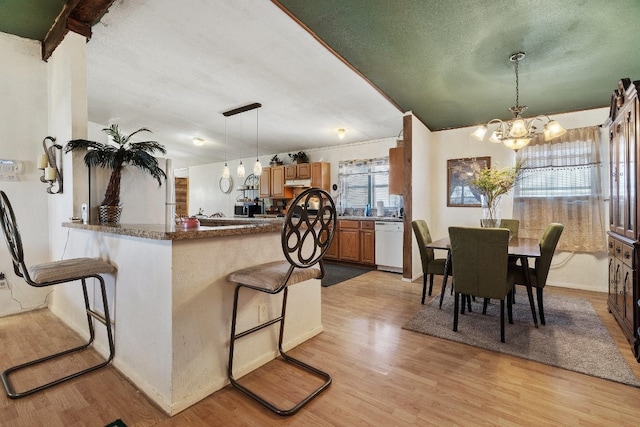 kitchen featuring pendant lighting, a breakfast bar, light hardwood / wood-style floors, kitchen peninsula, and a chandelier