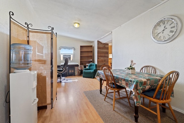 dining space featuring a textured ceiling, vaulted ceiling, a wood stove, and light hardwood / wood-style flooring