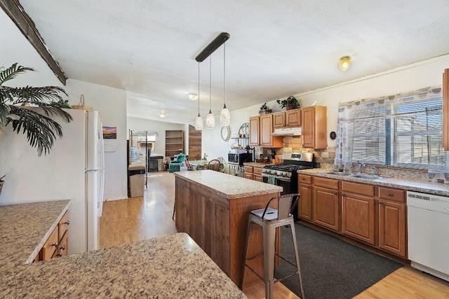 kitchen featuring white dishwasher, decorative light fixtures, gas range, light hardwood / wood-style flooring, and sink