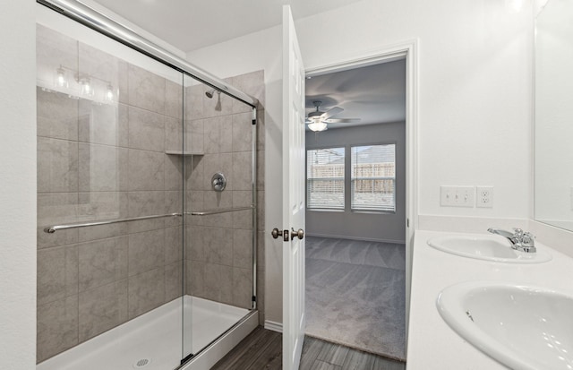 bathroom with wood-type flooring, a shower with door, ceiling fan, and sink