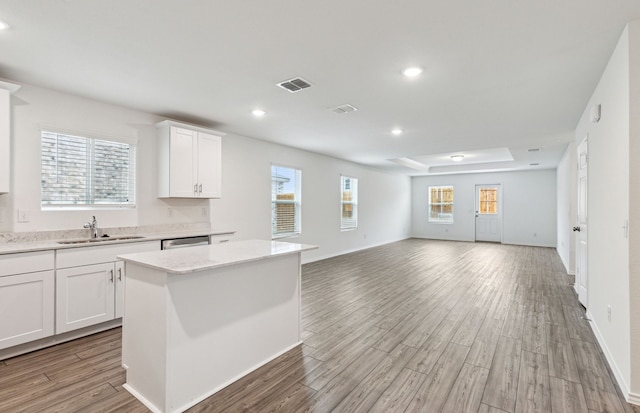 kitchen with white cabinets, a kitchen island, light hardwood / wood-style floors, and a healthy amount of sunlight