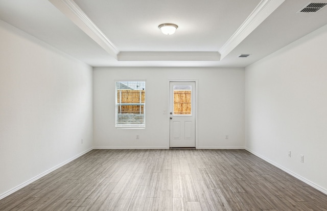 unfurnished room featuring hardwood / wood-style floors, a tray ceiling, and crown molding