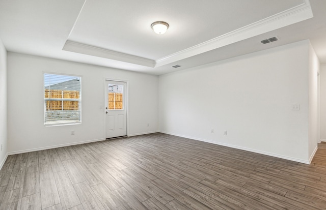 unfurnished room with hardwood / wood-style flooring, a raised ceiling, and crown molding