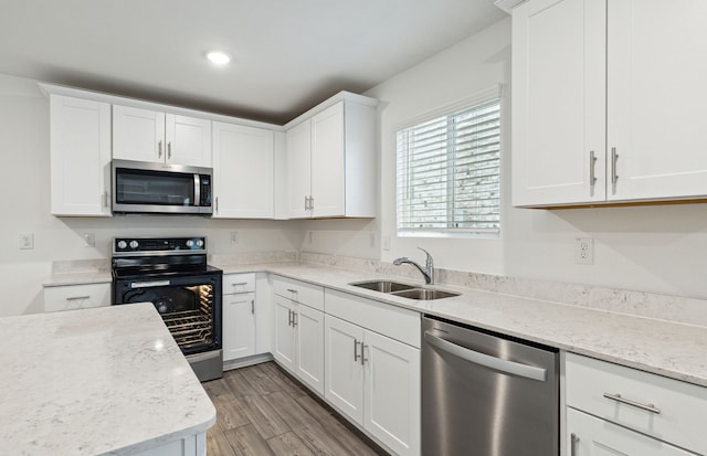 kitchen featuring light stone countertops, stainless steel appliances, dark wood-type flooring, sink, and white cabinets