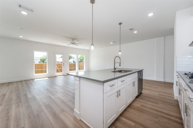 kitchen with a center island with sink, light wood-type flooring, white cabinets, sink, and appliances with stainless steel finishes