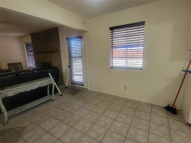 tiled bedroom featuring a textured ceiling, brick wall, a brick fireplace, and multiple windows