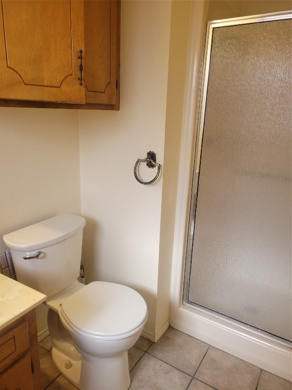 bathroom featuring vanity, tile flooring, a shower with shower door, and toilet