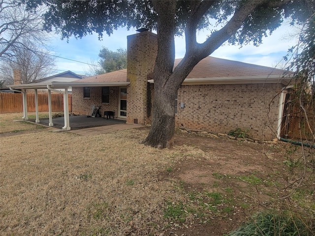 back of house featuring a carport and a lawn