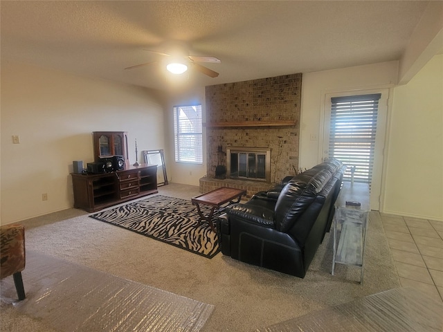 living room featuring ceiling fan, a fireplace, brick wall, a textured ceiling, and light colored carpet