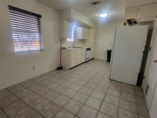 kitchen with white cabinetry, white fridge, light tile floors, and sink