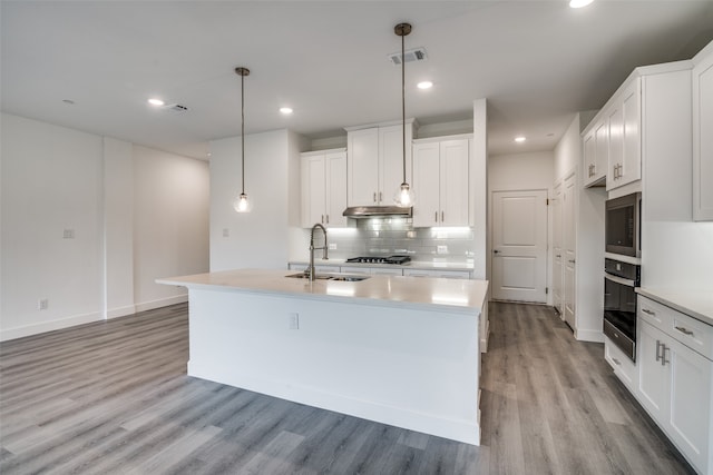 kitchen with oven, light hardwood / wood-style flooring, sink, decorative light fixtures, and white cabinetry